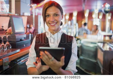 Focused barmaid using touchscreen till in a bar
