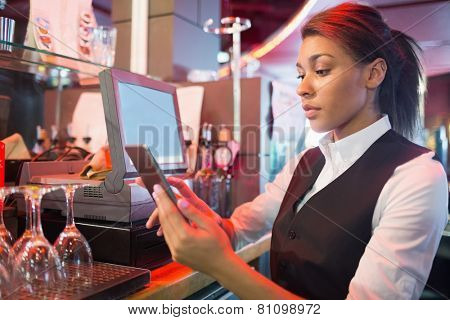 Pretty barmaid using touchscreen till in a bar