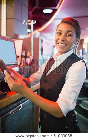 Pretty barmaid using touchscreen till in a bar