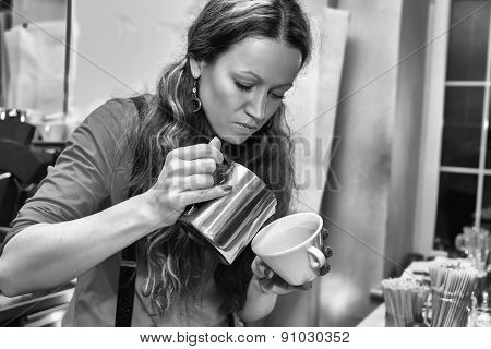 Female bartender in the workplace. Girl makes coffee using coffee machine.