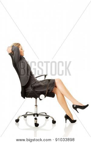 Businesswoman resting on armchair holding her neck