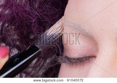 Application of powder on the model's face. Makeup artist in a beauty salon doing make-up special bru