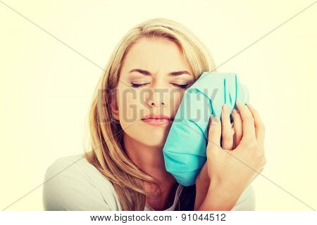 Woman heaving tooth ache, holding ice bag