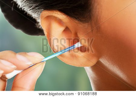 Beauty woman is cleaning her ear with cotton bud. 