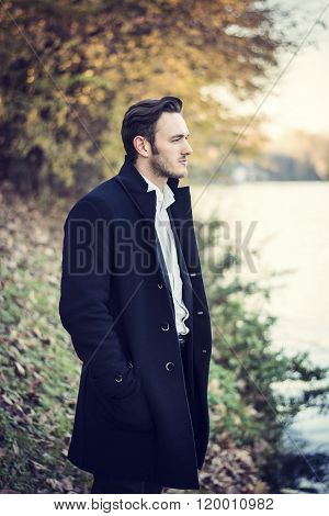 Young man outdoor in winter by lake or river