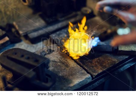 Jeweler melting gold and making jewelry heat