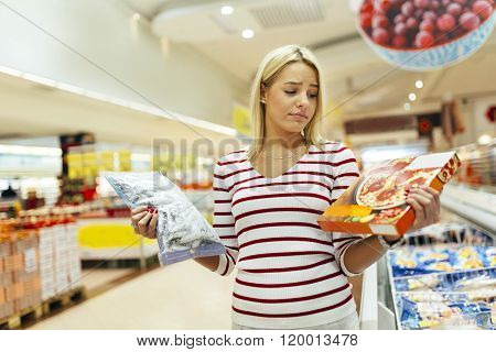 Beautiful woman deciding what to buy based on what is healthier