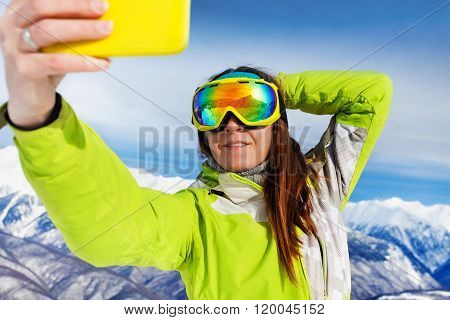 Skier woman take selfie with phone over mountains