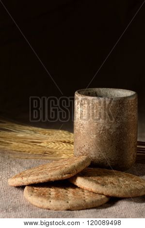 Symbols of communion: cup of wine, wheat and bread over table cloth