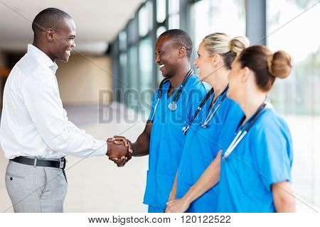 happy medical rep handshaking with group of doctors in hospital