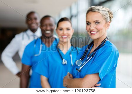 beautiful female doctor standing in a row with team
