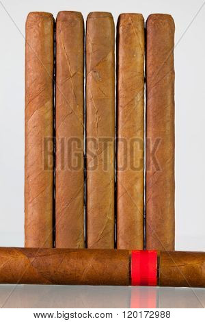 Different cigars on a glass table and white background