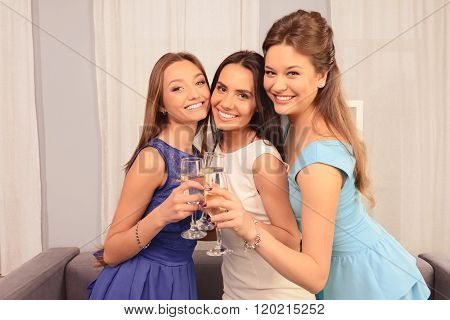 Three Happy Glamour Girls Holding Glasses With Shampagne And Smiling