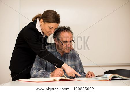 Young teacher explaining somethng to eldery man. Intergenerational transfer of knowledge.