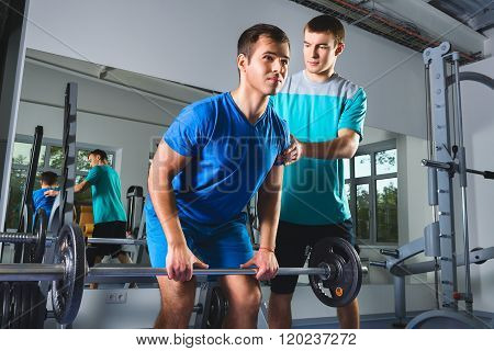 Muscular Man Lifting Deadlift In The Gym with instructor