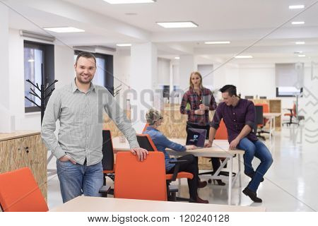 portrait of young businessman in casual clothes at modern  startup business office space,  team of people working together in background