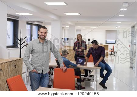 portrait of young businessman in casual clothes at modern  startup business office space,  team of people working together in background