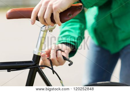 people, vehicle, eisure and lifestyle - close up of man adjusting fixed gear bike saddle high