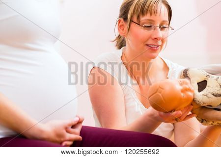 Midwife giving pregnant woman antenatal care for childbirth in practice 
