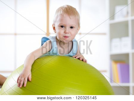 child boy playing with fitball indoors