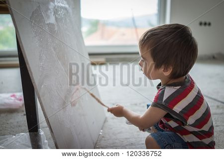 Little cute boy painting on a wall