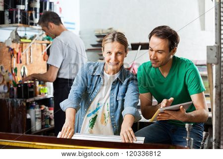 Worker Using Squeegee While Supervisor Holding Digital Tablet