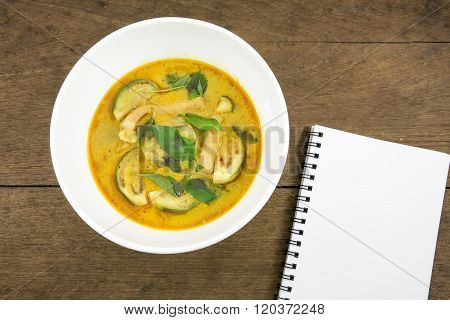 The delicious homemade Thai green curry with pork (Gang Keaw Wan) in white bowl and blank note book