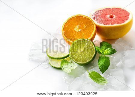 Citrus Fruits With Mint And Cubes Of Ice On White Copy Space Background