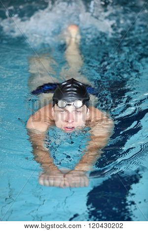 Close up of caucasian man practicing flutter kick with kick board in swimming indoor swimming pool.
