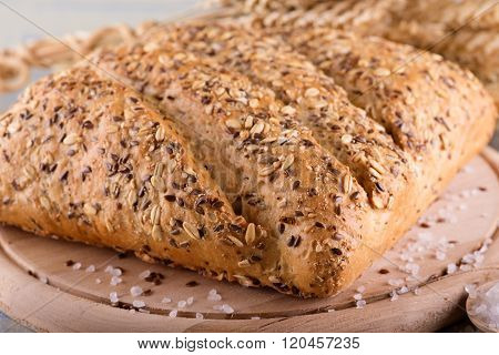Loaf Of Cereal Bread On Wooden Board With Salt Around