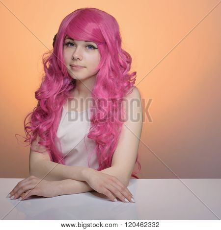 Girl with pink curly hair. Dolly-face woman white skin in pastel colors, looking down against pech b
