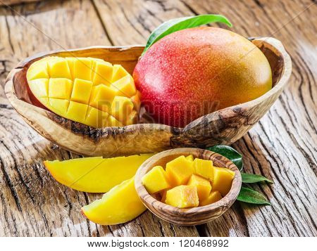 Mango fruit and mango cubes on the wooden table.