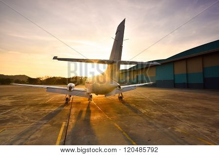 Small Aeroplane Infront Of Aircraft Hangar During Sunrise