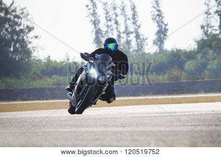 young man riding big bike motorcycle against sharp curve of asphalt high ways road with rural lake scene use for male adventure activities and motor sport hobby on holiday vacation