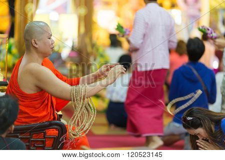SANGKHLABURI, THAILAND, JANUARY 24, 2016 :  A skilled Buddhist monk is blessing a woman  by throwing a rosary necklace around his neck in the Wat Wang Wiwekaram temple, Sanghklaburi, Thailand