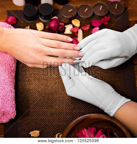 Closeup finger nail care by manicure specialist in beauty salon.