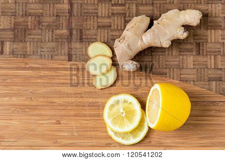 Sliced fresh ginger root and lemon on wooden cutting board natural remedy