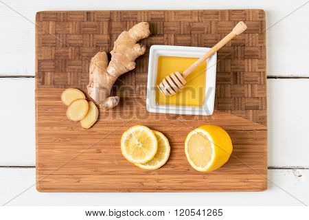 Fresh ginger root lemon and honey on wooden cutting board natural remedy.