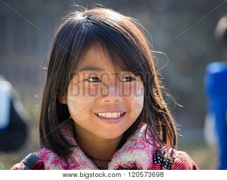 INLE LAKE MYANMAR - JANUARY 13 2016: Unidentified young Myanmar girl with thanaka on her smile face is happiness. Thanaka is a yellowish-white cosmetic paste made from ground bark.