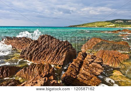 Red rocks and turquoise water at beach in San Pietro island, Sardinia