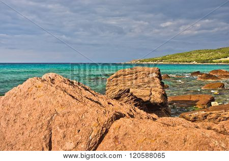 Red rocks and turquoise water at beach in San Pietro island, Sardinia