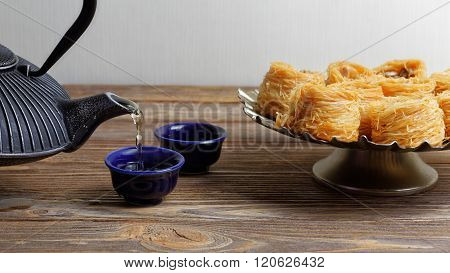 Green Tea Is Poured Into The Bowl Near The Oriental Sweets