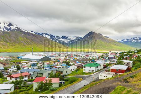 Mighty fjords with mountains covered by snow rise above the town of Olafsfjordur, Northern Iceland