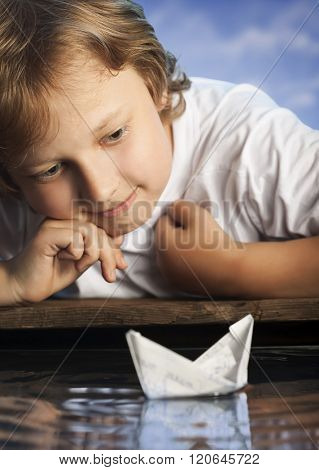 boy play in paper ship in water puddel