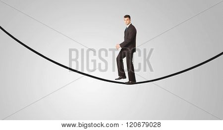 A confident smiling salesman balancing on black wire in clear grey empty space concept