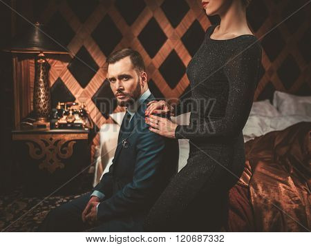 Well-dressed couple in luxury bedroom interior.