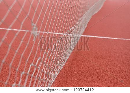 Detail Of Net Tennis On Field Made From Red Granule Rubbe. Selective Focus