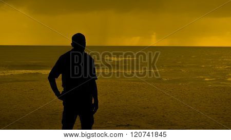 Man Goes To The Sea On Dark Sand Beach Under Beautiful Colorful Cloudy Sky