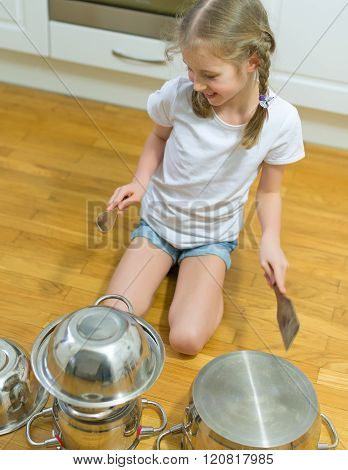 Little girl playing drums on pots and pans in the kitchen.
** Note: Visible grain at 100%, best at smaller sizes
