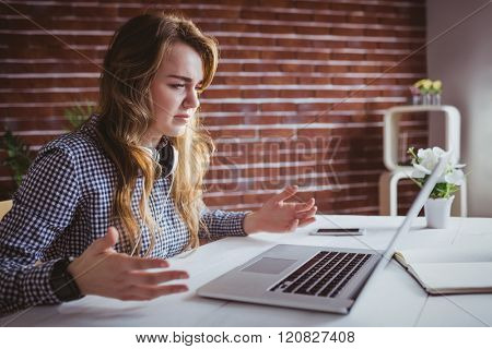 Young hipster businesswoman misunderstanding her laptop at her desk in office